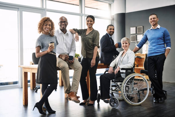 A group of diverse workers smile towards the camera.   